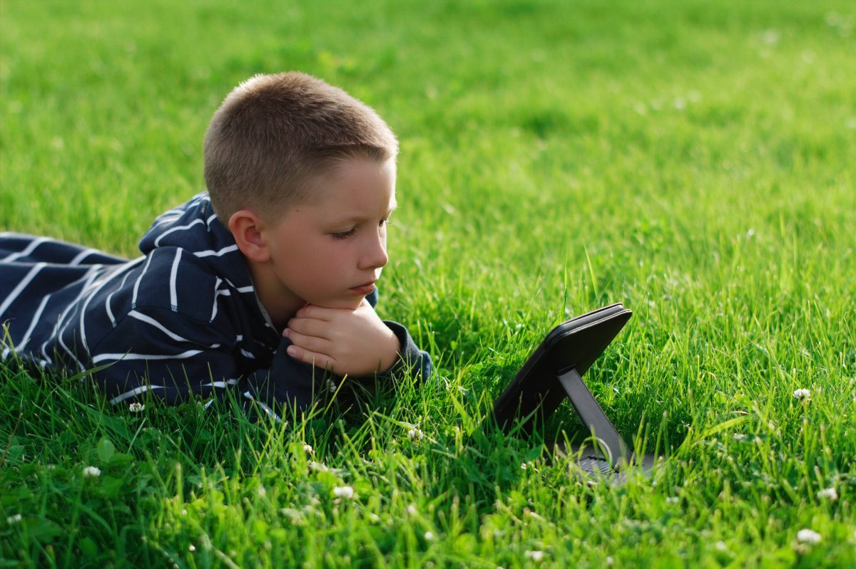 boy in grass with tablet