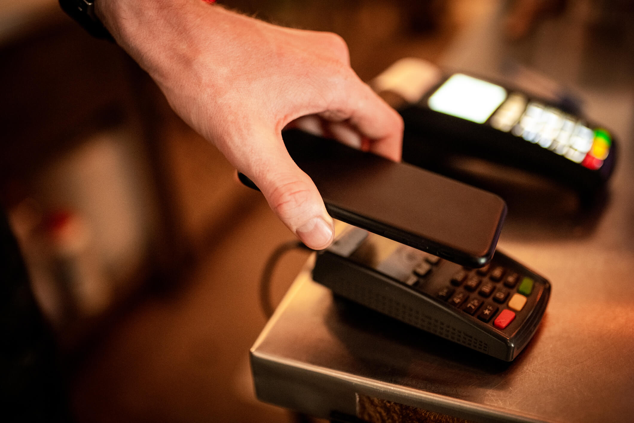 Person holding phone above a payment system